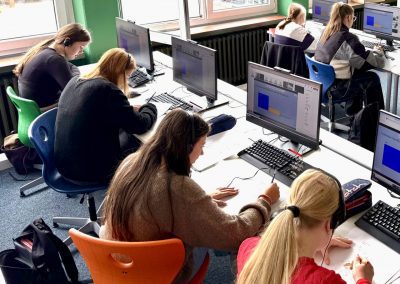 Schülerinnen und Schüler sitzen an Computern während des Online-Workshops