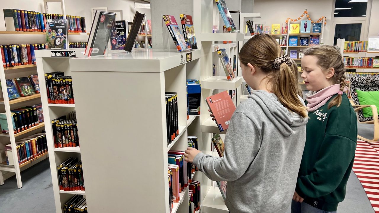 Büchereibesuch der 5. Klassen 2025 Zwei Schülerinnen schauen sich ein Besuch an